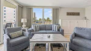 A living room with a grey sofa set, a coffee table, wicker baskets, and a view of the city.