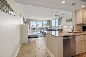 Una cocina moderna con lavavajillas, una zona de comedor con mesa y sillas, y vista a la playa.