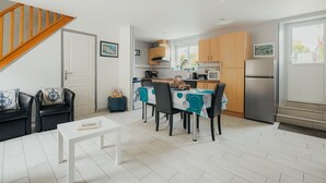 A compact kitchen with a dining area, a staircase, and a view of the outdoors. - Cottage 'Gite Les Dauphins À Matignon' with Private Terrace, Private Garden and Wi-Fi (Matignon)