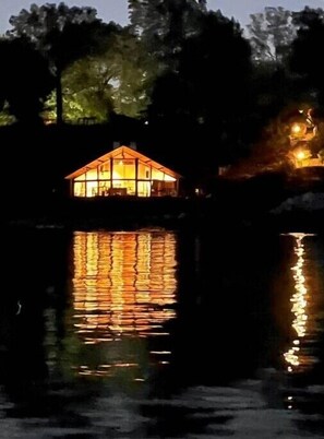 A house with a glass facade reflecting on the water.