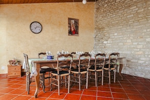A dining area with a wooden table set for six, surrounded by six wooden chairs. A clock and a painting are on the wall. - Holiday Home 'Gîte Koala' with Private Pool, Wi-Fi & Air Conditioning (Marans)