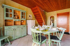 A dining area with a wooden staircase, green cabinets, and a table set for four. - Holiday Home 'Gîte Le Petit Sableau' with Shared Pool & Spa, Private Terrace, Wi-Fi (MARANS)