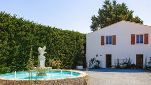 A building with a stone fountain, a statue, and a hedge. - Holiday Home 'Gîte Le Petit Sableau' with Shared Pool & Spa, Private Terrace, Wi-Fi (MARANS)