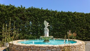 A stone fountain with a statue in the center, surrounded by a circular stone wall and a pool of water. - Holiday Home 'Gîte Le Petit Sableau' with Shared Pool & Spa, Private Terrace, Wi-Fi (MARANS)