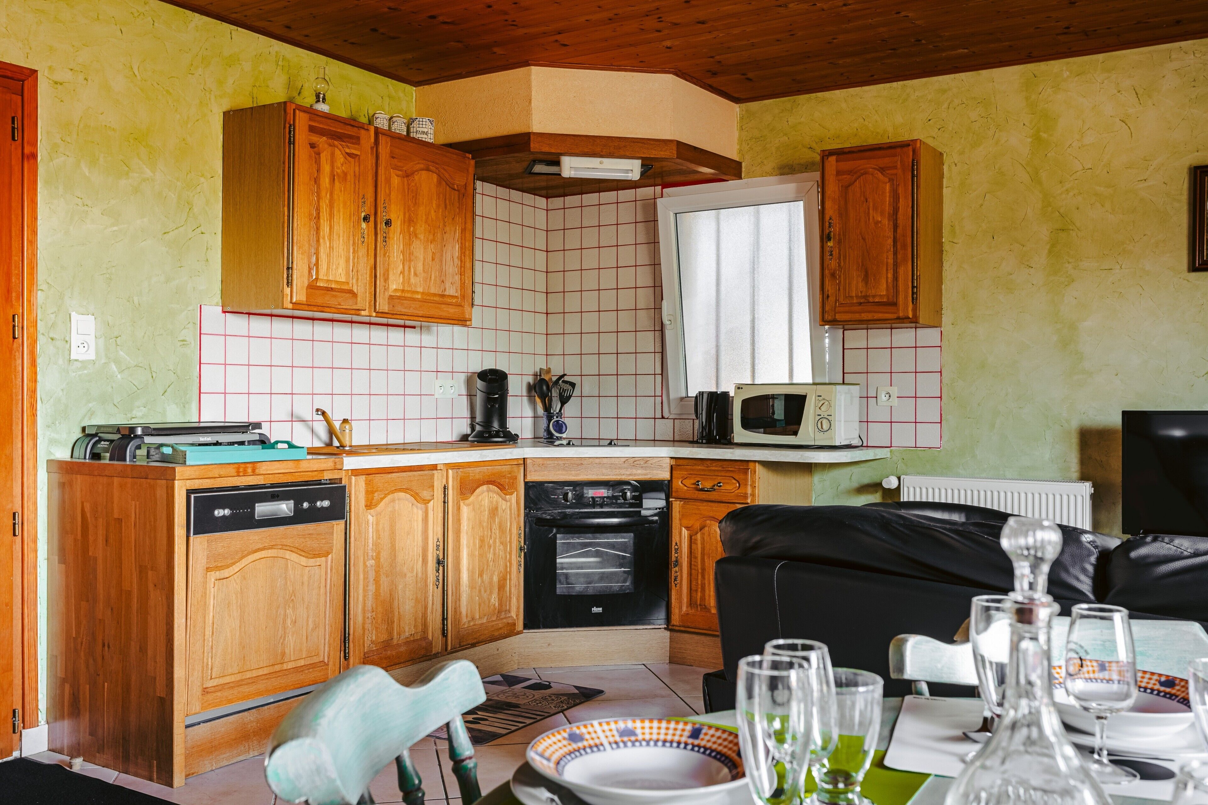 Une cuisine compacte avec des meubles en bois, un lave-vaisselle, un four et un four à micro-ondes.