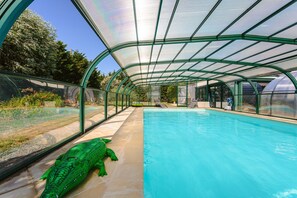 A swimming pool with a glass enclosure, surrounded by a garden. - Holiday Home 'Gîte Le Petit Sableau' with Shared Pool & Spa, Private Terrace, Wi-Fi (MARANS)