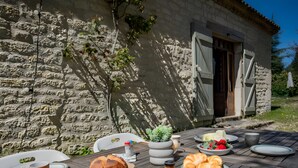 A rustic outdoor dining area with stone walls, wooden furniture, and a variety of food and drink items. - La Bergerie de Montcuq – Private Pool & Jacuzzi, Panoramic Views (Montcuq-en-Quercy-Blanc)