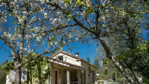 A two-story house with a balcony, surrounded by trees and a clear sky. - La Bergerie de Montcuq – Private Pool & Jacuzzi, Panoramic Views (Montcuq-en-Quercy-Blanc)