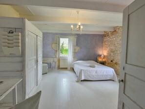 Una camera da letto con un letto, una finestra, un lampadario e un muro in pietra.