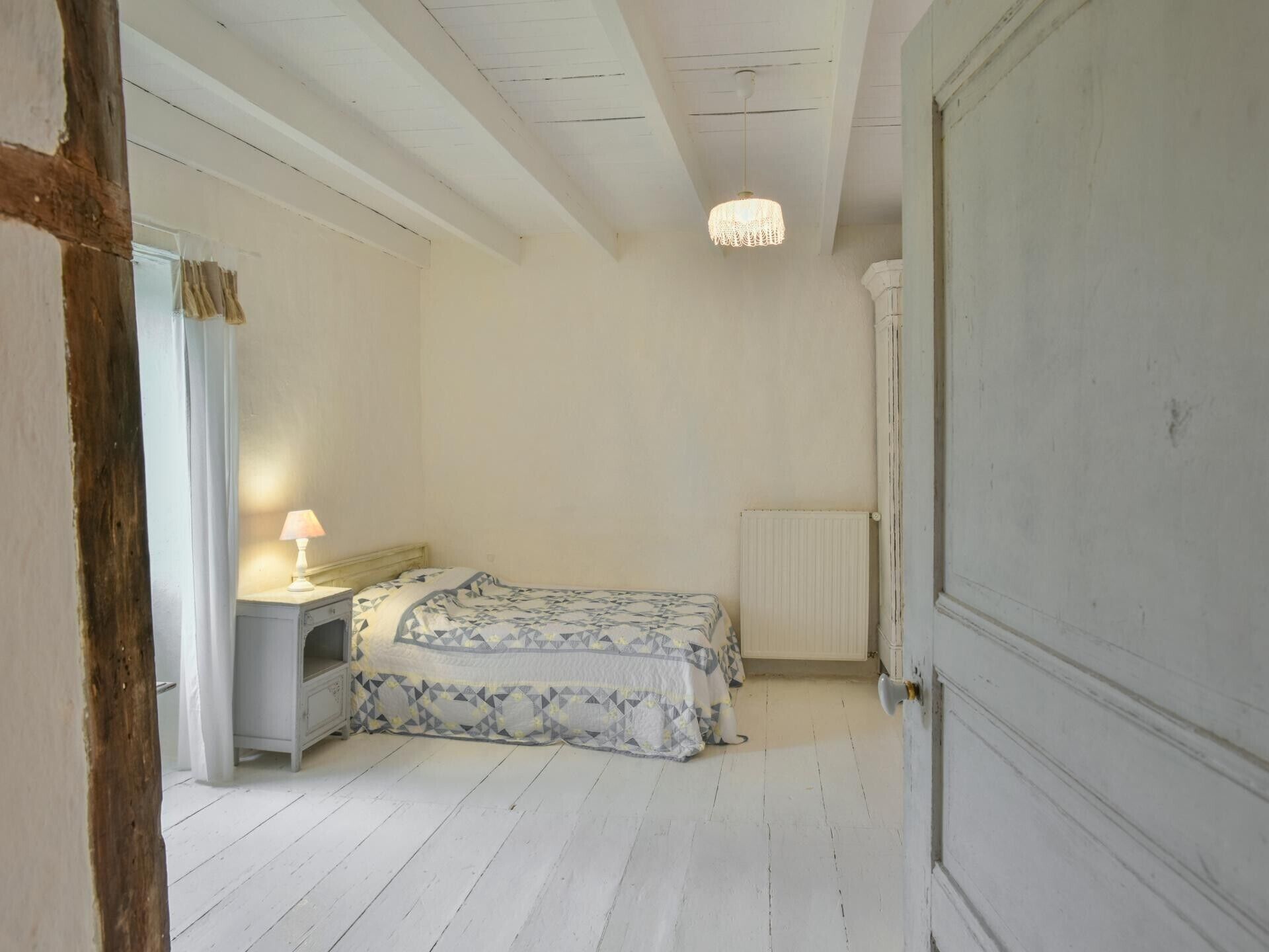 Une chambre à coucher avec un lit, une table de chevet avec une lampe, un radiateur et une armoire.