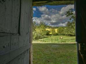 Una rustica stalla con vista su un prato verde e alberi.