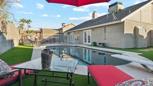 A backyard with a swimming pool, a glass table, and red outdoor furniture. - 4 Bed Shuffleboard& Private Pool Retreat in Peoria (Peoria)