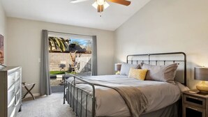 A bedroom with a bed, bedside tables, a ceiling fan, and a view of the outdoors. - 4 Bed Shuffleboard& Private Pool Retreat in Peoria (Peoria)