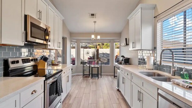 A modern kitchen with white cabinets, a stainless steel range, and a large window providing natural light. - 4 Bed Shuffleboard& Private Pool Retreat in Peoria (Peoria)