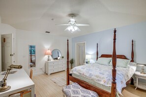 Un dormitorio con cama con dosel, un escritorio con lámpara, un aparador y un espejo.