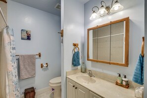 Un baño con lavamanos, espejo y perchero para toallas.