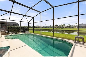 A swimming pool with a clear view of the surrounding neighborhood, including houses and a body of water.