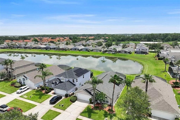 A residential area with houses, a pond, and a clear sky.