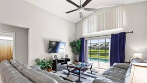 Uma sala de estar moderna com televisão de tela plana, sofás de couro, uma mesa de centro e um ventilador de teto.