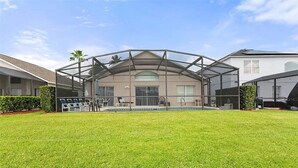 Uma casa com área externa coberta, piscina e gramado bem cuidado.