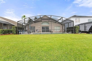 A house with a covered outdoor area, a swimming pool, and a well-maintained lawn.