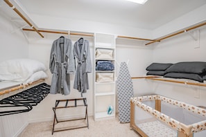 A neatly organized bedroom with a bed, a changing table, a wardrobe, and a crib.