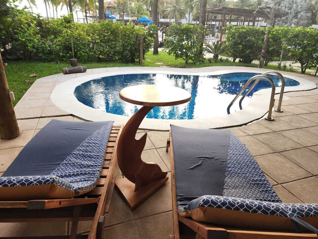 Un área de piscina con sillones de descanso y una mesa.