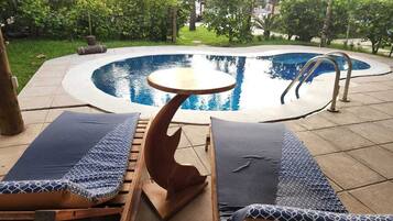 Un área de piscina con sillones de descanso y una mesa.