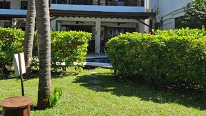 A multi-story building with a covered outdoor area, palm trees, and a small pool. - Los Cabos Monterrico byLAurora Inn (Taxisco)