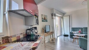 Um espaço de estar compacto com cozinha compacta, área de jantar e sala de estar com sofá e uma mesinha.
