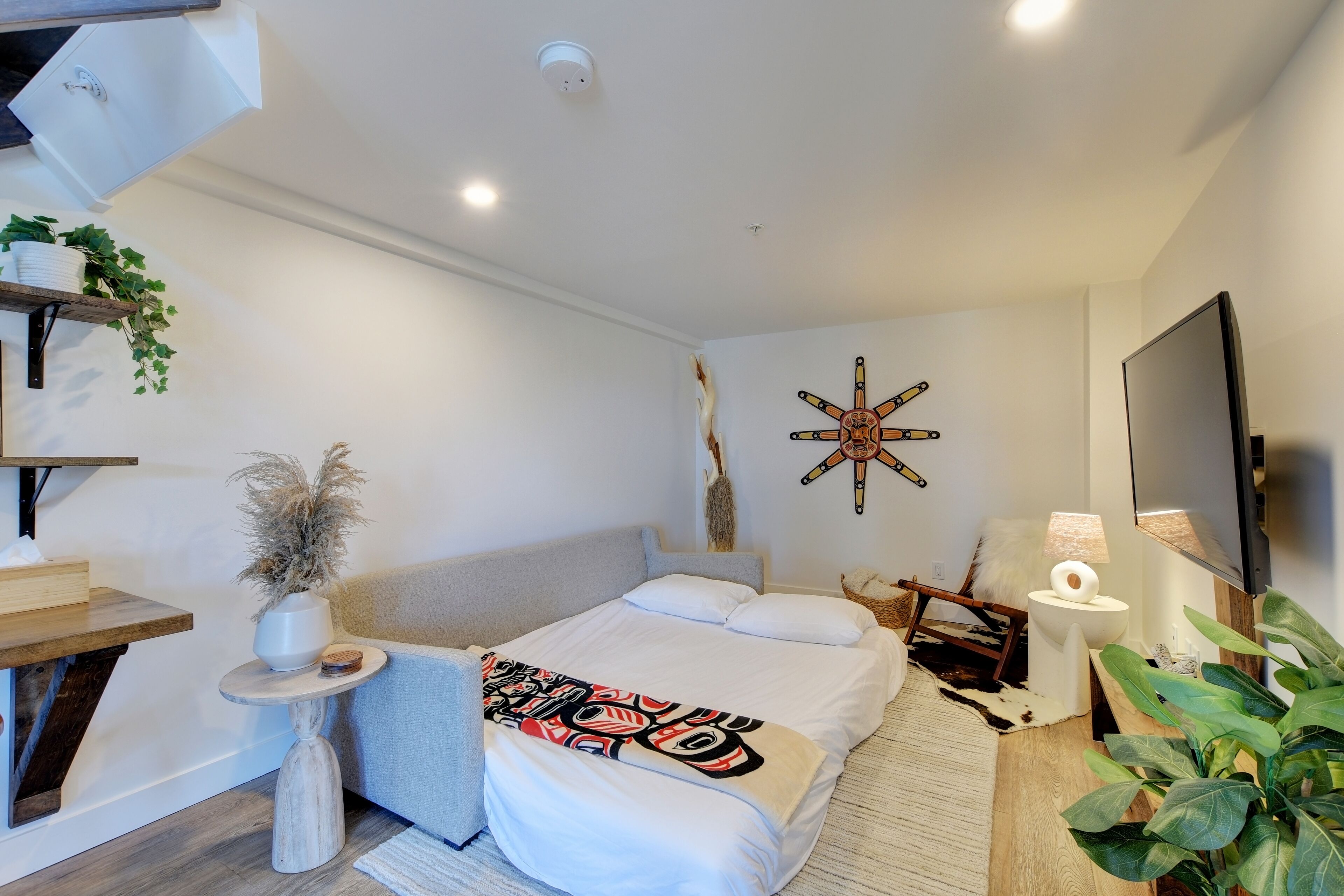 A modern bedroom with a bed, bedside table, TV, and decorative wall art.