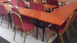 A dining area with tables and chairs, a pillar, and a television on the wall.
