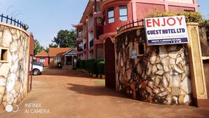 A guest hotel with a reception area, a stone wall entrance, and a sign advertising the hotel.