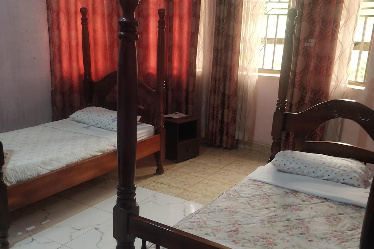 A bedroom with two wooden beds, a nightstand, and a window with curtains.