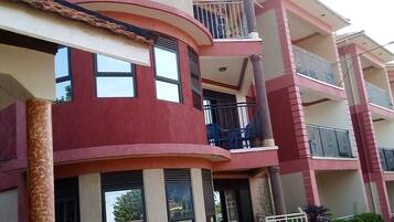 Un edificio residencial de varios pisos con balcones y un muro de piedra en la base.