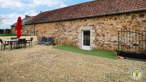 Ein Steinhaus mit Ziegeldach, Kiesterrasse und Außenbestuhlung.