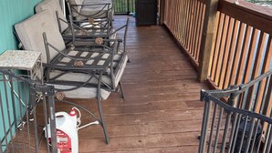 A covered outdoor deck with metal chairs and a table, overlooking a body of water with boats and cabins in the background. - Come stay on the water and create your own tales to share for a lifetime! (New Tazewell)