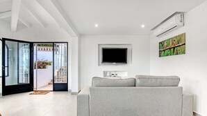Ein modernes Wohnzimmer mit einem grauen Sofa, einem Flachbildfernseher und einer Klimaanlage.