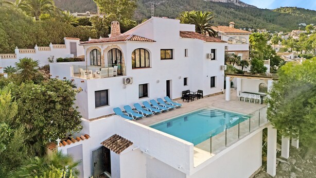 Eine moderne Villa mit Swimmingpool, Sitzgelegenheiten im Freien und Bergblick.