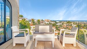 Ein Balkon mit Korbmöbeln und Blick auf die Stadt.