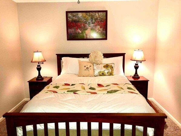 A neatly made bed with a floral bedspread, two bedside lamps, and a framed picture above the bed. - MAY'S FLOWERS , Stylish 4 Bedroom house, High Speed Internet, Equipped Kitchen (Tyler)