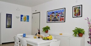 Een eethoek met een witte tafel, stoelen en een potplant.