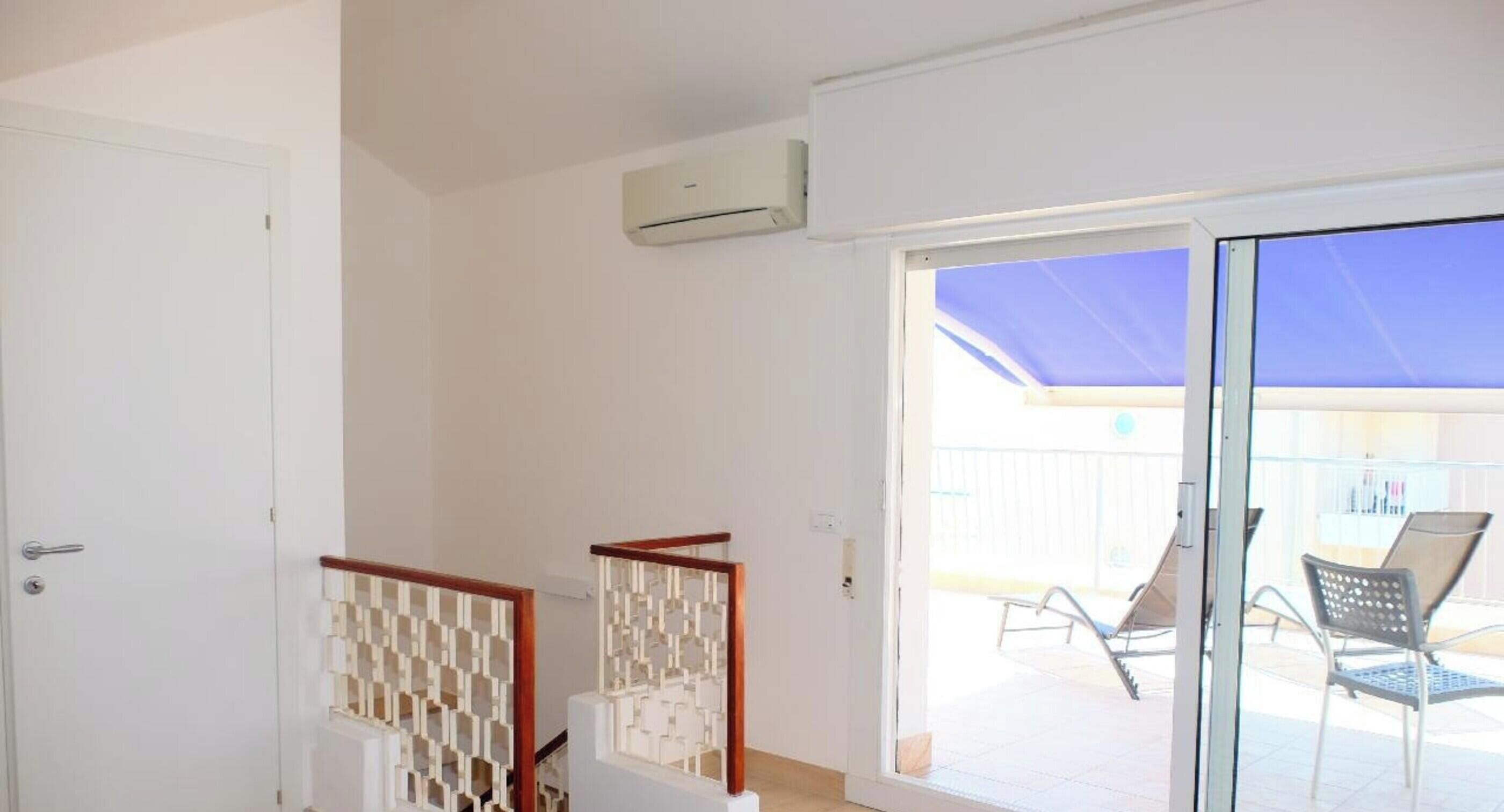 A room with a sliding glass door leading to an outdoor area with a pool and lounge chairs.