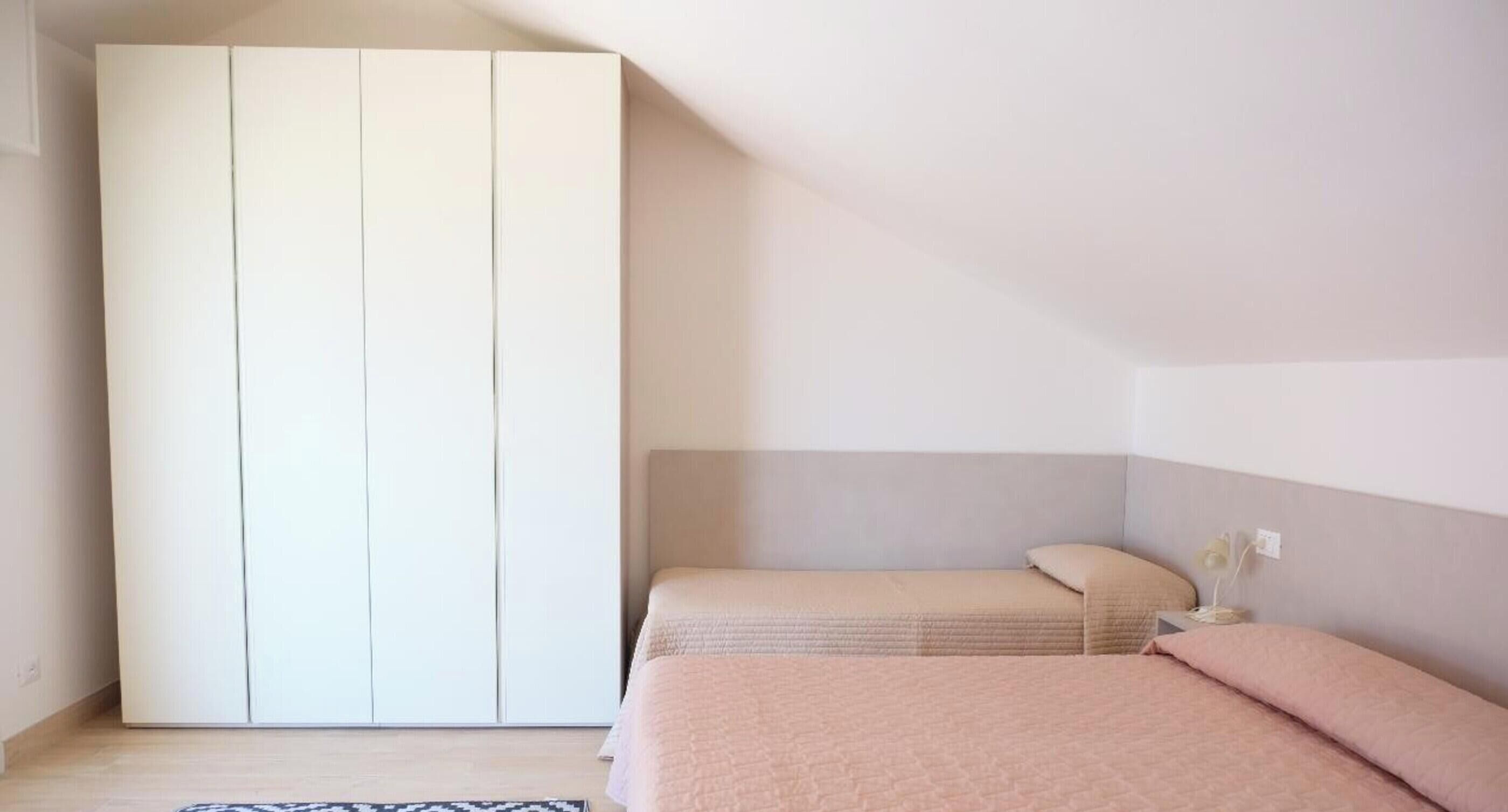 A bedroom with a bed, a wardrobe, and a bedside table.