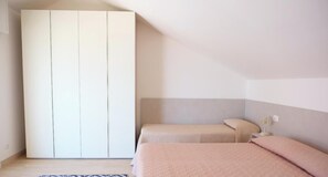 Een slaapkamer met een bed, een kledingkast en een nachtkastje.