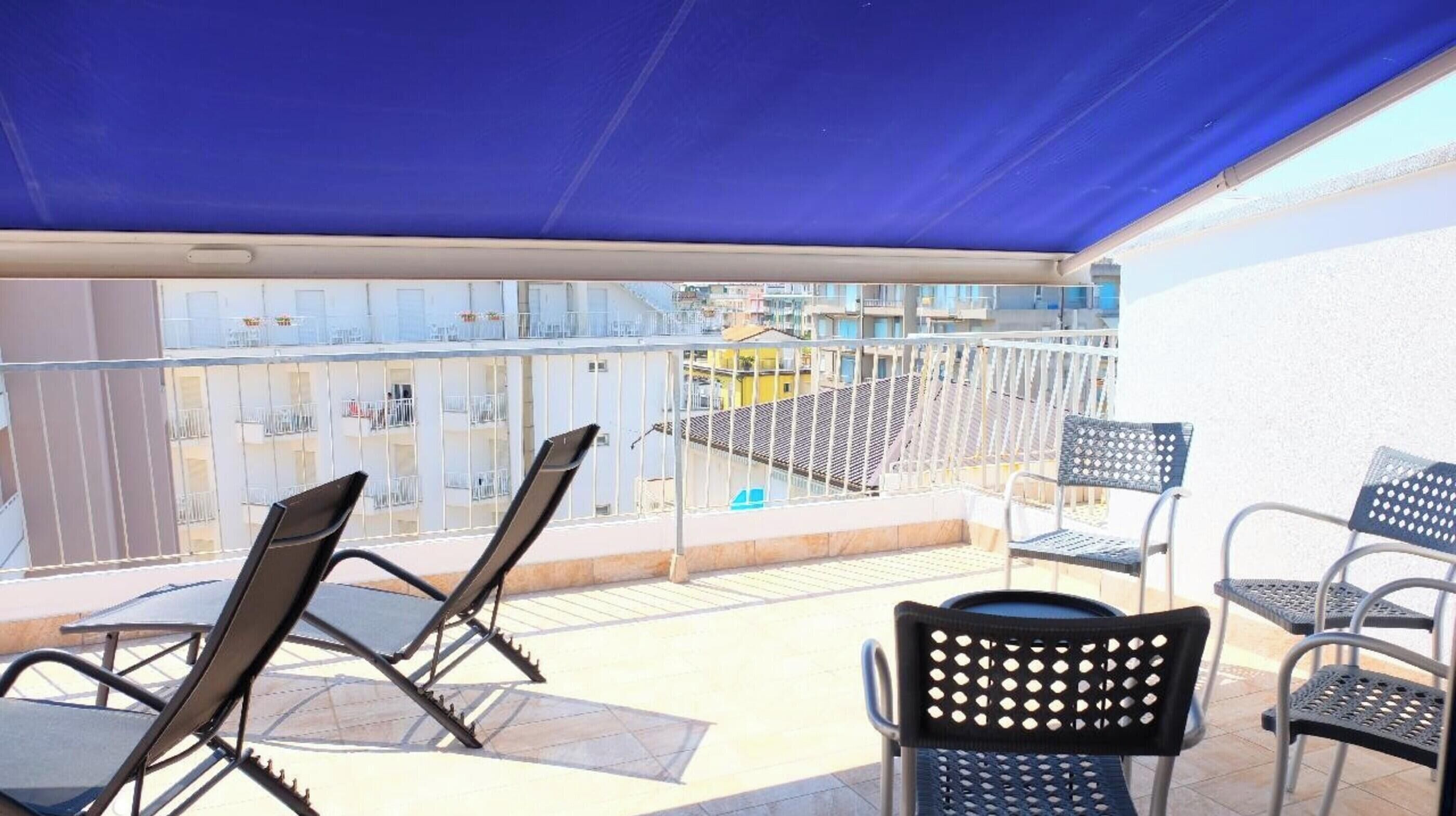 A balcony with chairs and a table, overlooking a cityscape.