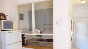 Kompakti keittiö, jossa on mikroaaltouuni, jääkaappi, pesuallas ja liesi.