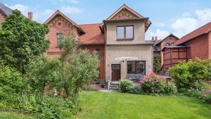 A two-story house with a brick facade, a small front porch, and a garden with various plants and flowers. - Awesome apartment in Blankenburg (Harz) with WiFi (Blankenburg (Harz))