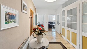 A hallway with a radiator, a vase with flowers, framed pictures, and a door leading to a living area. - Awesome apartment in Blankenburg (Harz) with WiFi (Blankenburg (Harz))