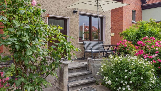 A patio with a bench and a table, a concrete staircase, and a variety of flowering plants. - Awesome apartment in Blankenburg (Harz) with WiFi (Blankenburg (Harz))